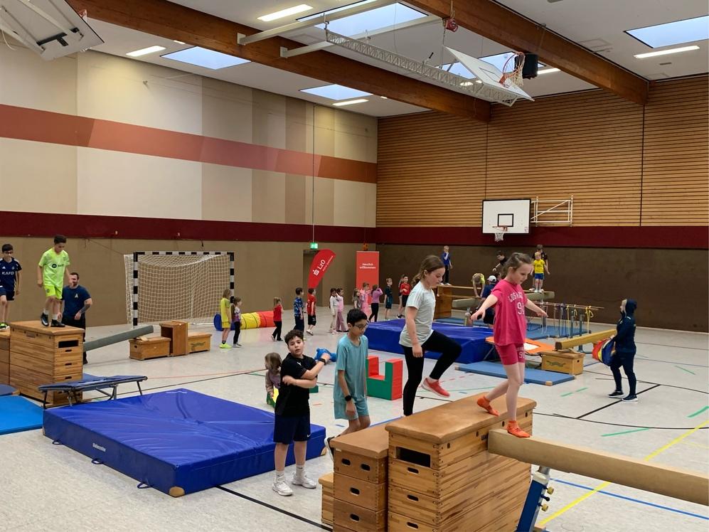 Kinder haben Spa&szlig; auf dem Gymnastikboden mit verschiedenen Turnger&auml;ten.