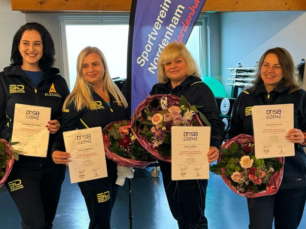Vier Frauen in Sportkleidung halten Blumensträuße und Zertifikate vor einem Banner des Sportvereins Nordenham.