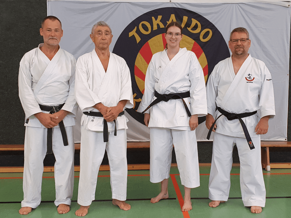 Vier Karateka in traditioneller Kleidung stehen zusammen und l&auml;cheln f&uuml;r ein Gruppenfoto.
