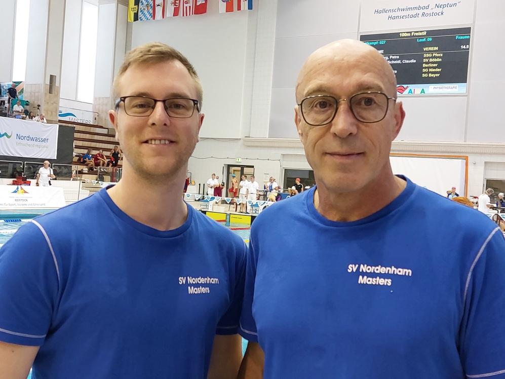 Zwei M&auml;nner im blauen Trikot des SV Nordenham Masters stehen am Schwimmbeckenrand w&auml;hrend eines Wettkampfs.