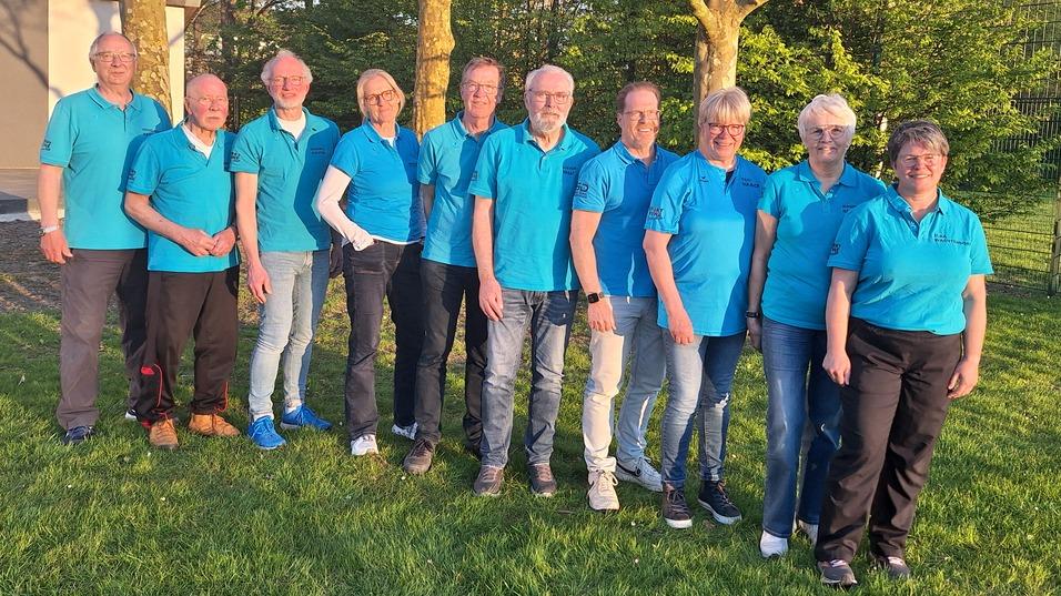 Gruppenshot von zehn Personen in blauen Oberteilen vor einem Schild des Sportvereins Nordenham e.V. im Freien.
