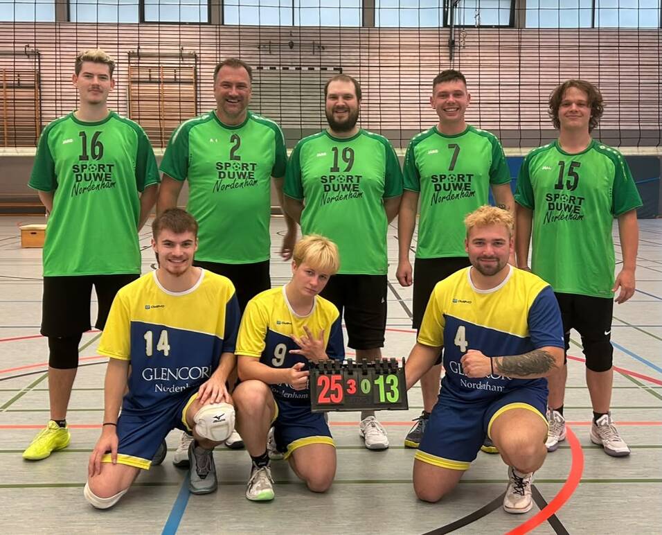 F&uuml;nf M&auml;nner in gr&uuml;nen Trikots und drei M&auml;nner in gelb-blauen Trikots posieren in einer Sporthalle, zwei knien und halten eine Anzeigetafel mit der Zahl '25:13'.