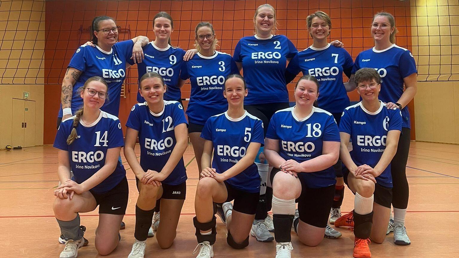 Teamfoto einer Volleyballmannschaft, Spielerinnen in einheitlichen Trikots, l&auml;cheln in die Kamera auf dem Spielfeld