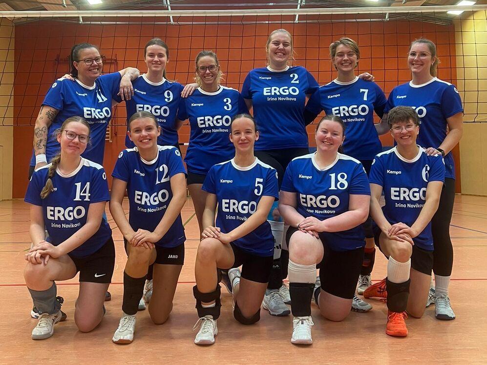 Teamfoto einer Volleyballmannschaft, Spielerinnen in einheitlichen Trikots, l&auml;cheln in die Kamera auf dem Spielfeld