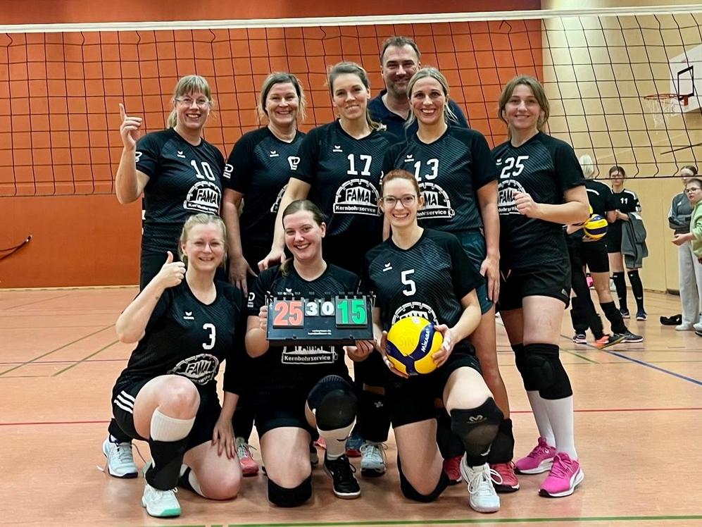 Volleyballmannschaft posiert nach dem Spiel mit Punktestand 25 zu 15 auf einem Sportplatz in einer Halle.