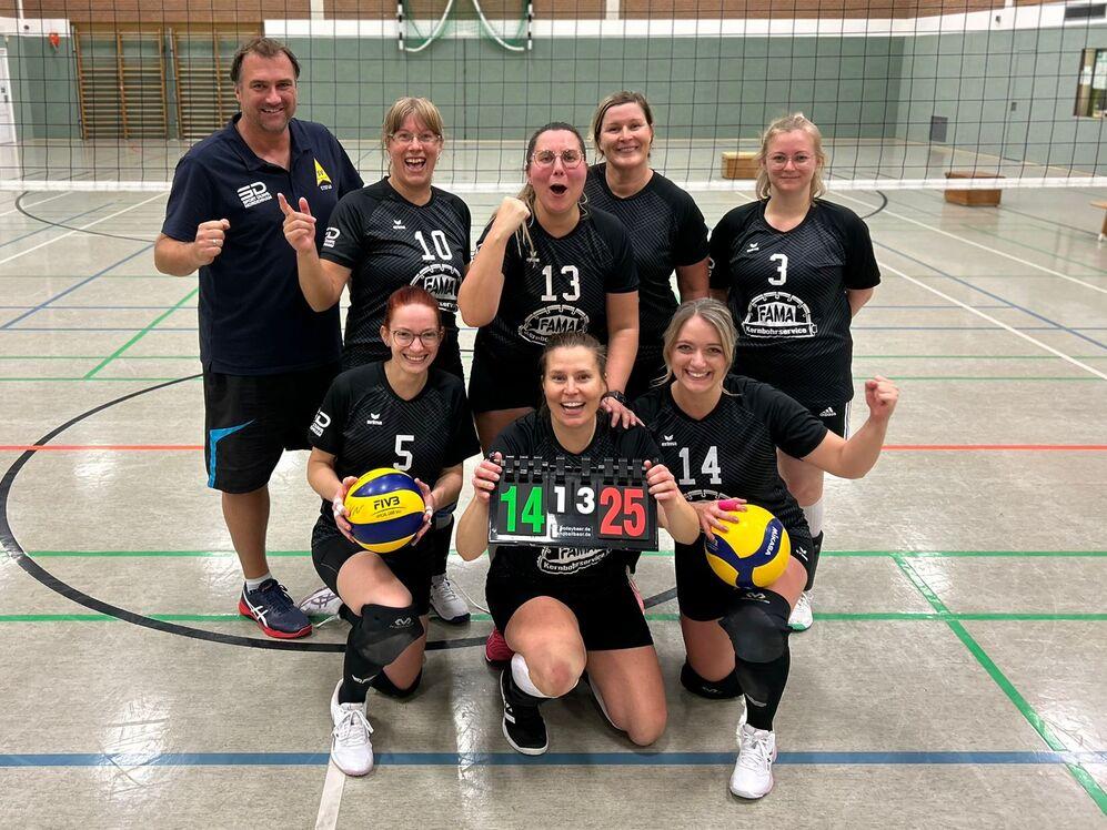 Sechsk&ouml;pfiges Volleyballteam in Schwarz posiert gl&uuml;cklich mit Ball und Punktestand in einer Sporthalle.