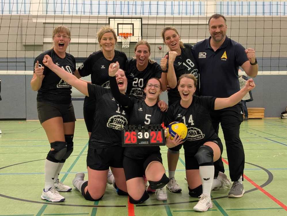 Volleyballmannschaft posiert f&uuml;r ein Gruppenfoto nach dem Sieg auf dem Spielfeld.