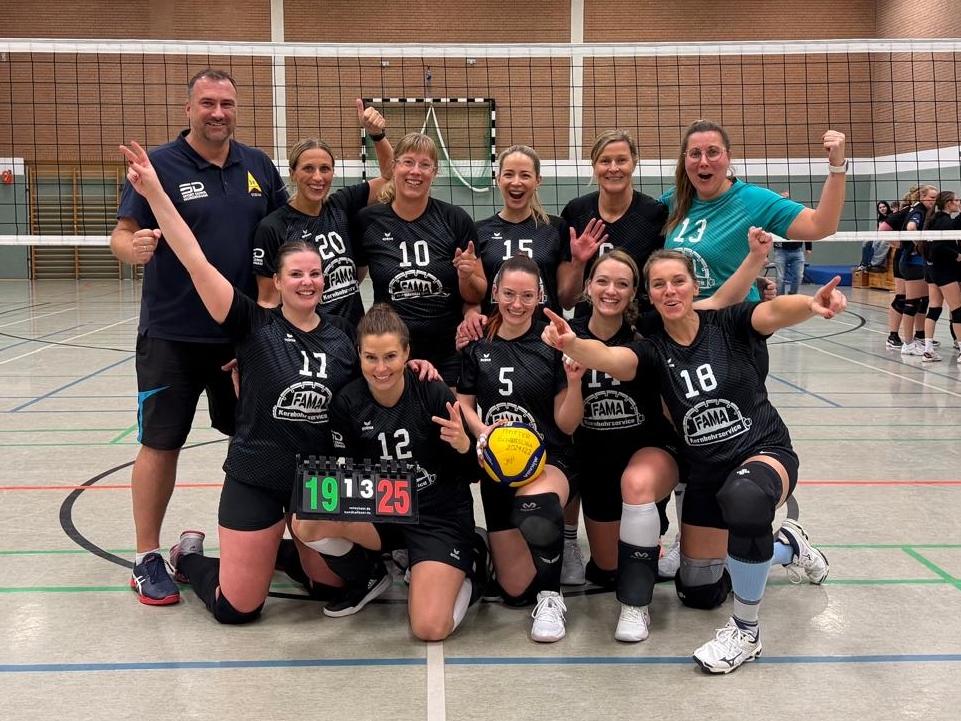 Volleyballmannschaft posiert jubelnd für ein Foto in einer Sporthalle.