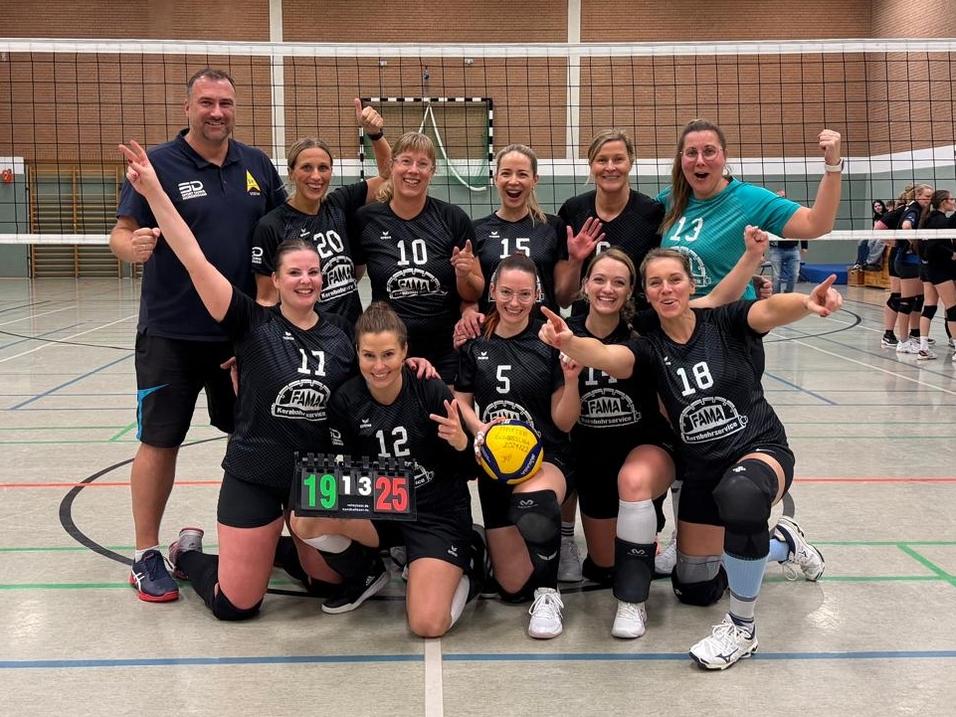 Volleyballmannschaft posiert jubelnd für ein Foto in einer Sporthalle.