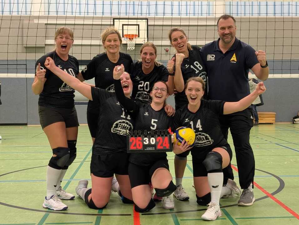 Volleyballmannschaft posiert f&uuml;r ein Gruppenfoto nach dem Sieg auf dem Spielfeld.