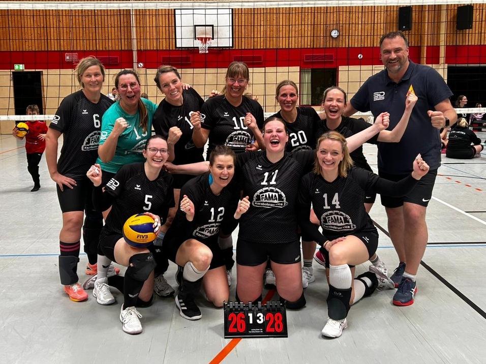 Gruppe von Volleyballspielern in Sportkleidung posiert in einer Halle vor einem Volleyballnetz und einem Basketballkorb.