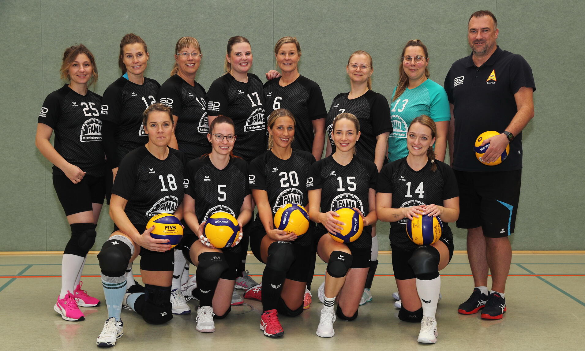 Die Volleyballmannschaft steht mit ihrem Trainer f&uuml;r ein Foto zusammen. Alle Mitglieder sind in Teamkleidung gekleidet.
