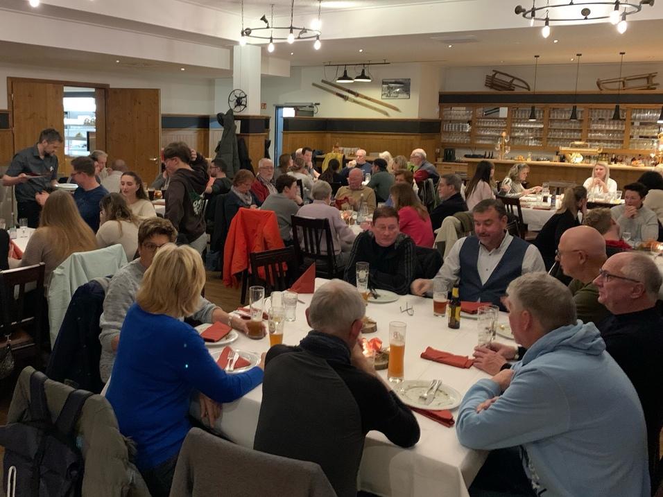 Ein geräumiges Restaurant mit vielen Tischen, an denen Gäste essen und trinken, umgeben von warmem Licht.