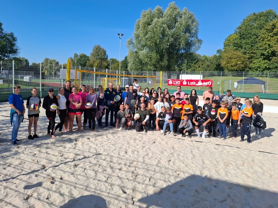 Eine Gruppe von Menschen posiert f&uuml;r ein Foto w&auml;hrend der Er&ouml;ffnung der Beachsportanlage.