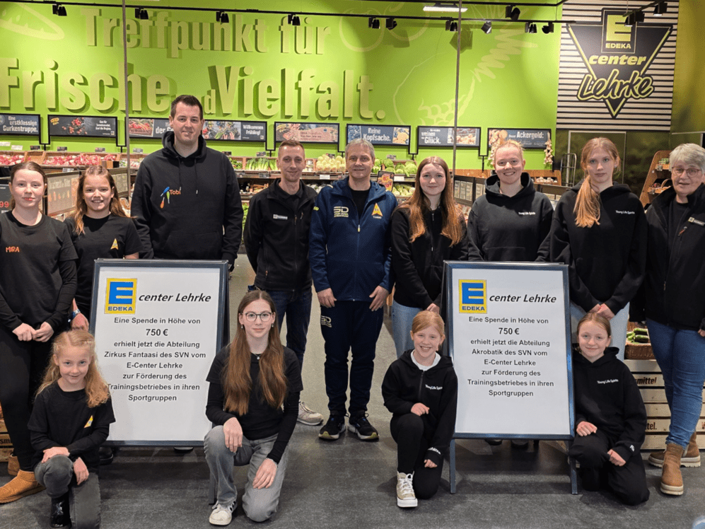 &Uuml;bergabe von zwei Schecks f&uuml;r die Nachwuchsarbeit im Sportverein. Kinder und Erwachsene auf dem Bild vor einem gr&uuml;nen Hintergrund.