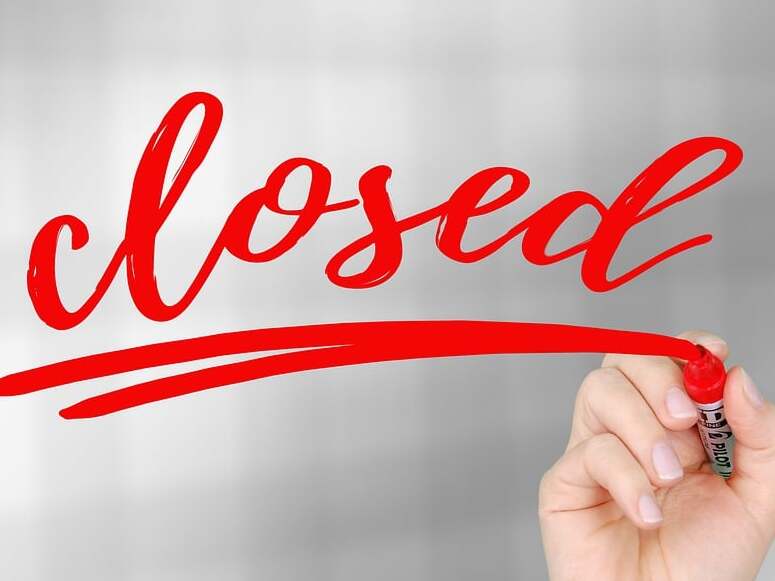 Hand, die mit einem roten Marker das Wort &bdquo;closed&ldquo; auf einen unscharfen Hintergrund schreibt.